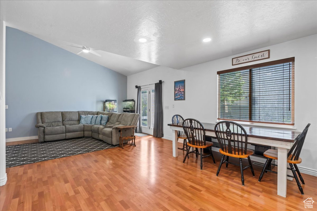 Dining space featuring plenty of natural light, wood finished floors, a textured ceiling, ceiling fan, and vaulted ceiling