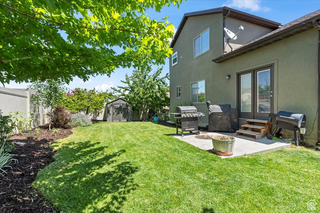 Fenced backyard featuring a storage unit, a patio area, and entry steps