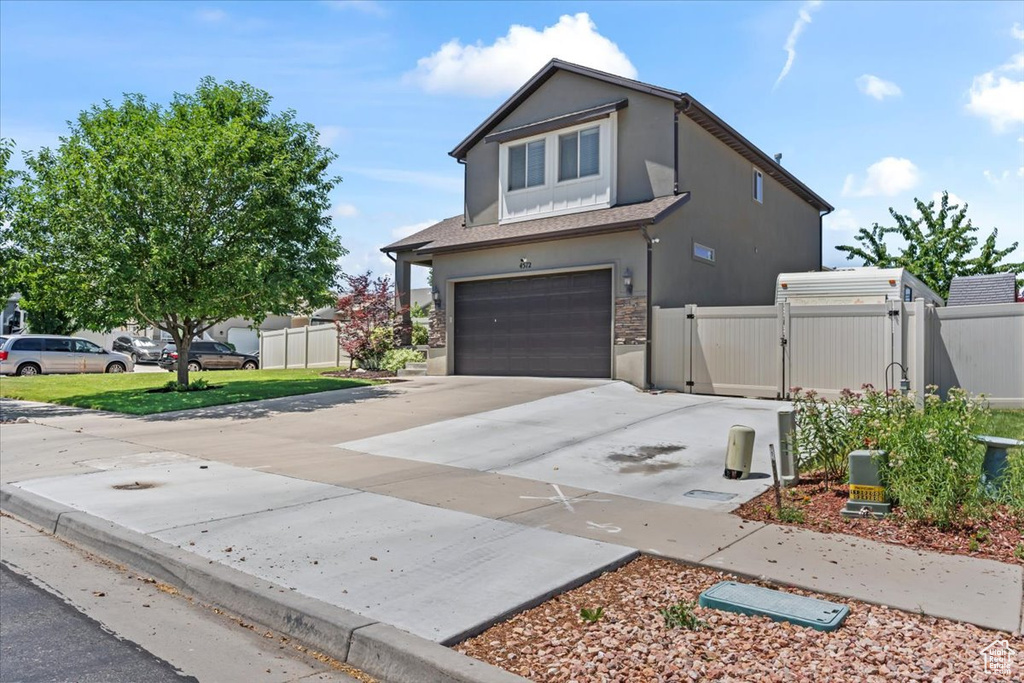 View of front of house featuring a gate, a garage, stucco siding, stone siding, and concrete driveway