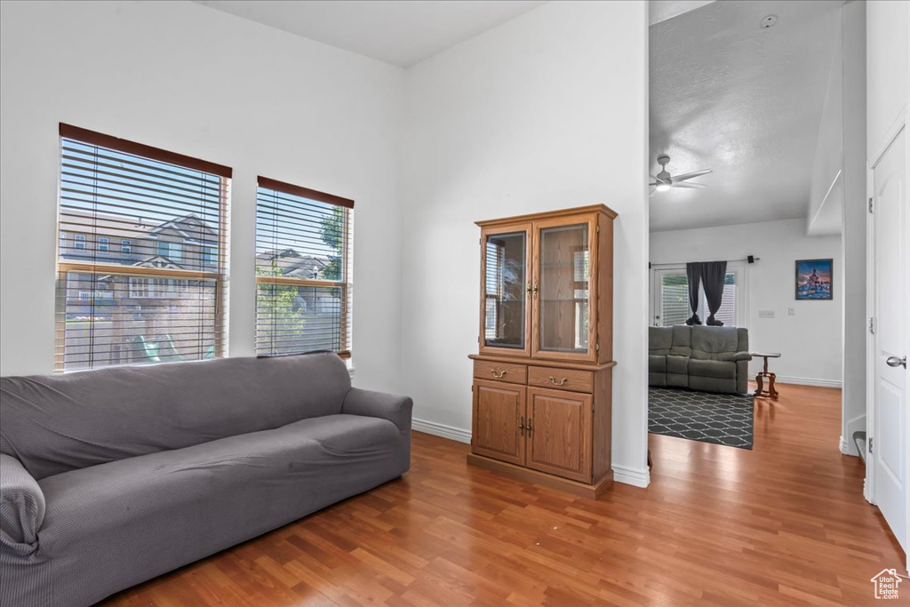 Living area featuring light wood-style floors, a ceiling fan, and a towering ceiling