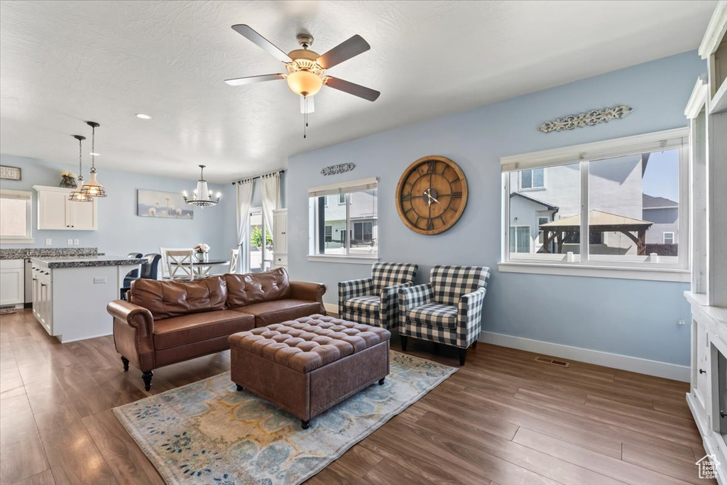 Living room with ceiling fan, wood finished floors, and a chandelier