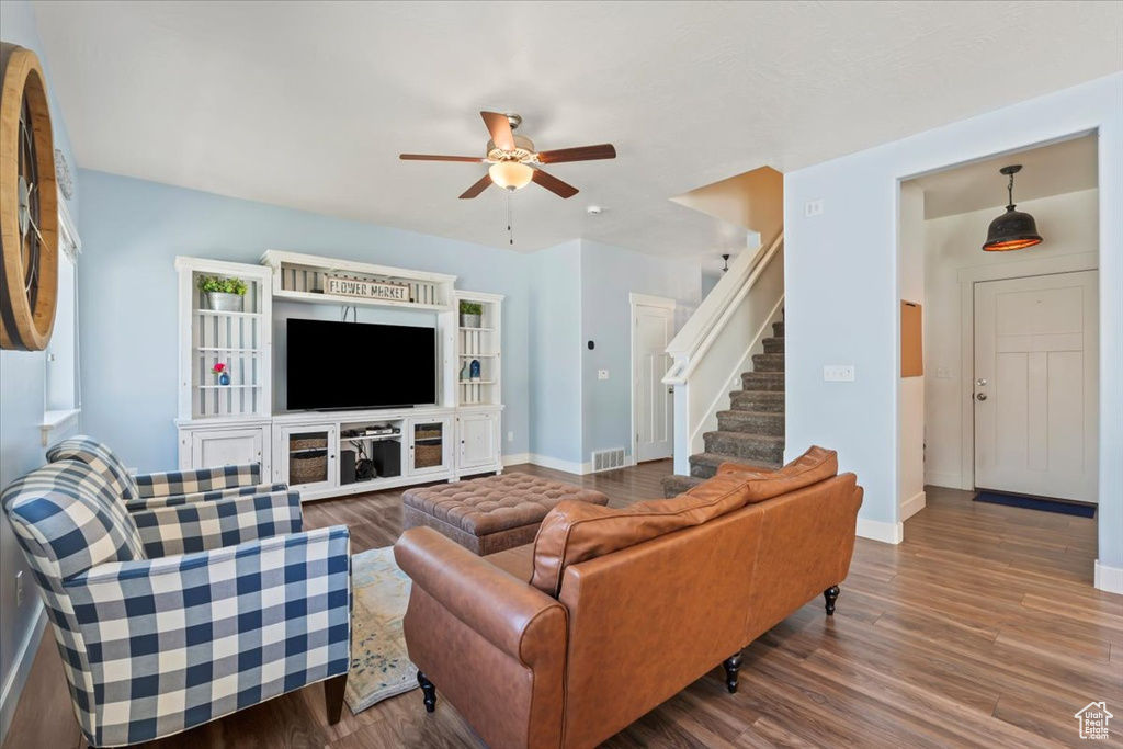 Living area featuring ceiling fan, wood finished floors, and stairs