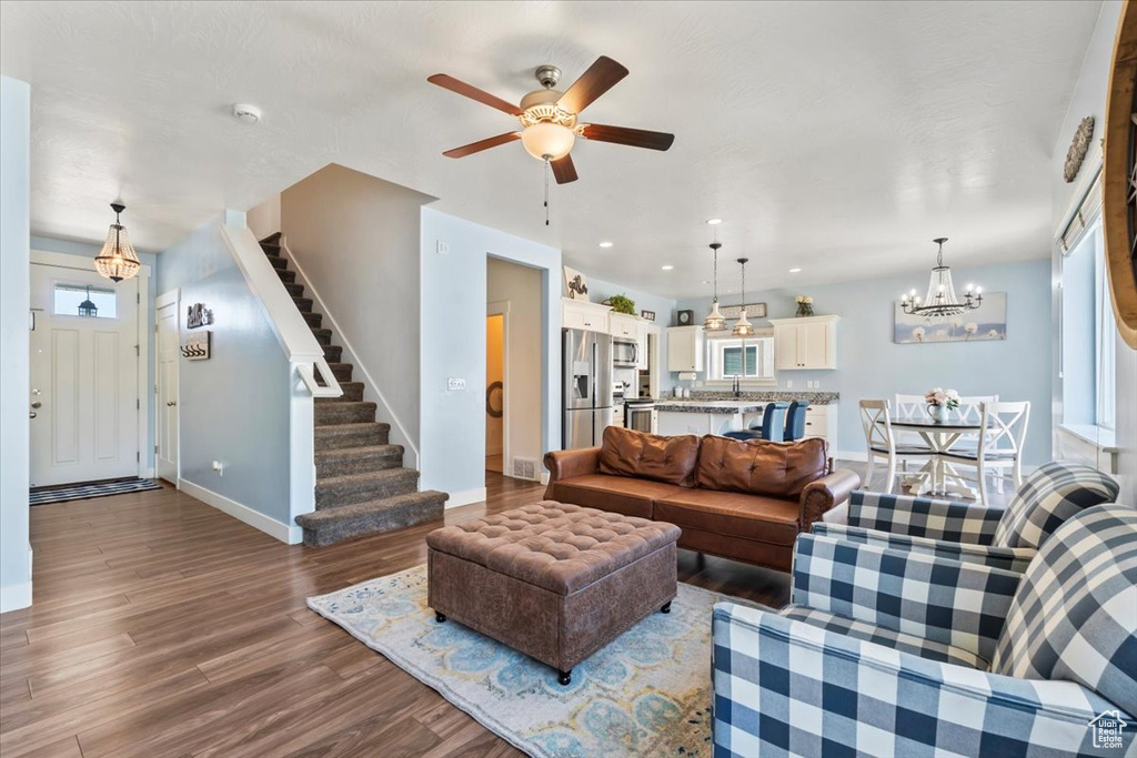 Living room featuring wood finished floors, stairs, a chandelier, ceiling fan, and recessed lighting