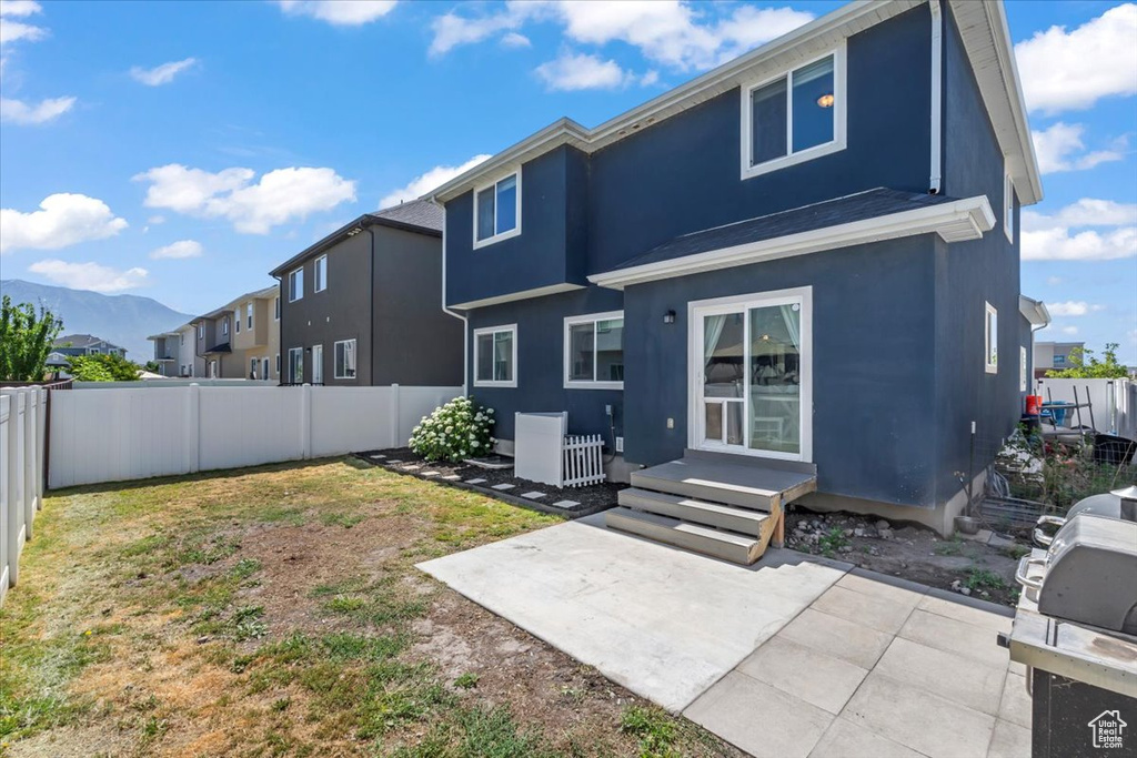 Back of house with stucco siding, a fenced backyard, a patio, and a mountain view