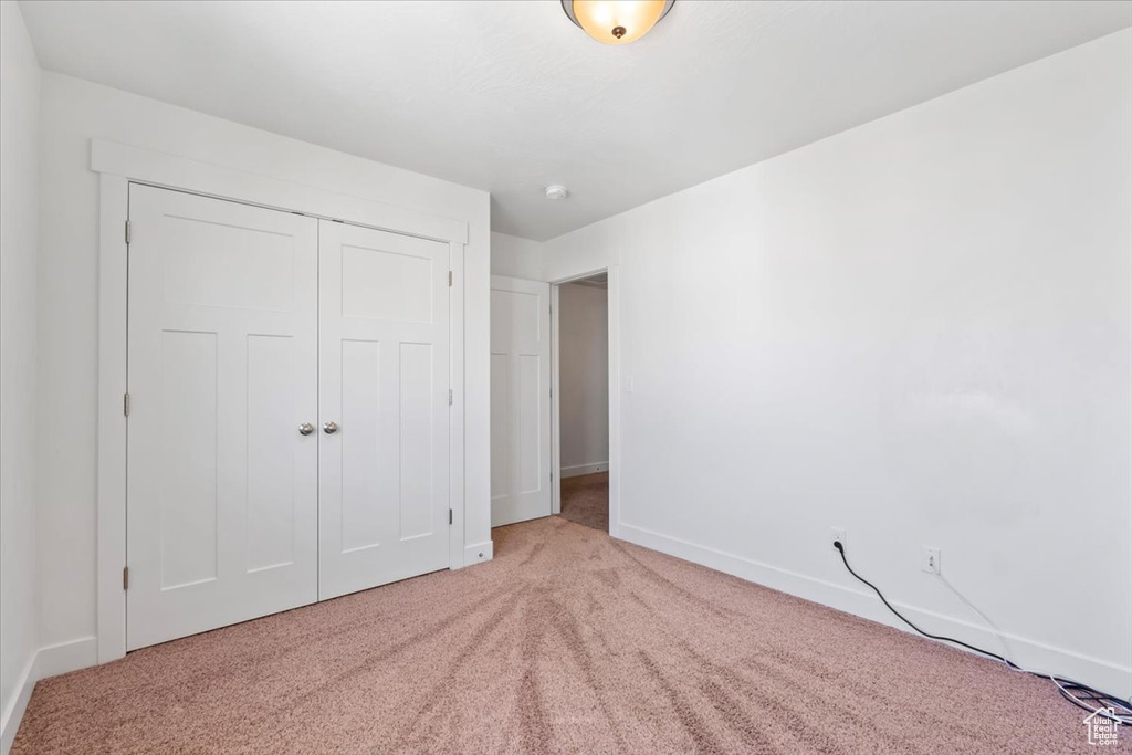 Unfurnished bedroom featuring light carpet and a closet