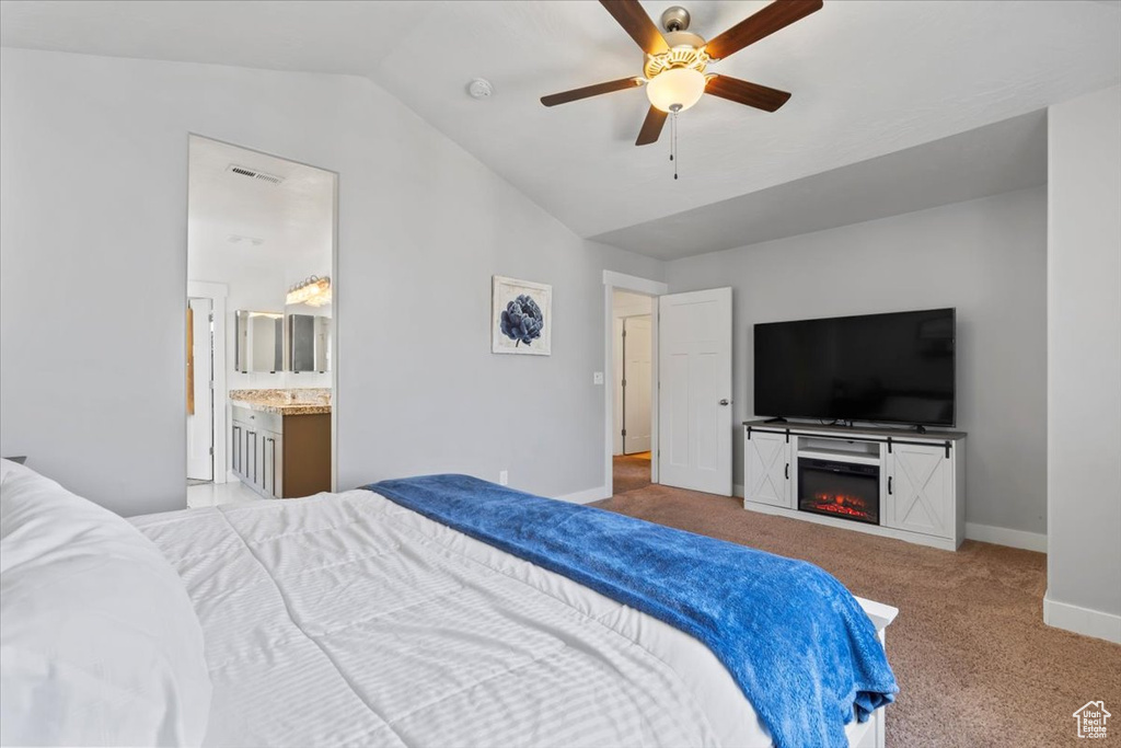 Bedroom featuring lofted ceiling, carpet, a glass covered fireplace, ceiling fan, and ensuite bathroom