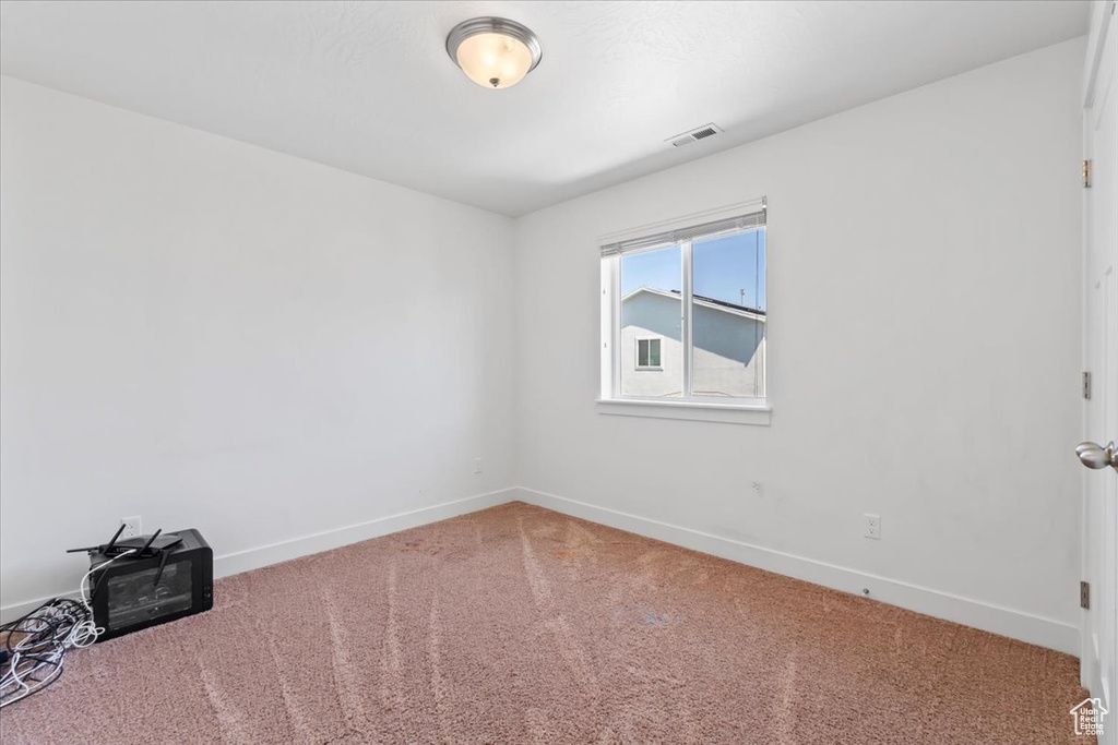 Carpeted spare room featuring baseboards