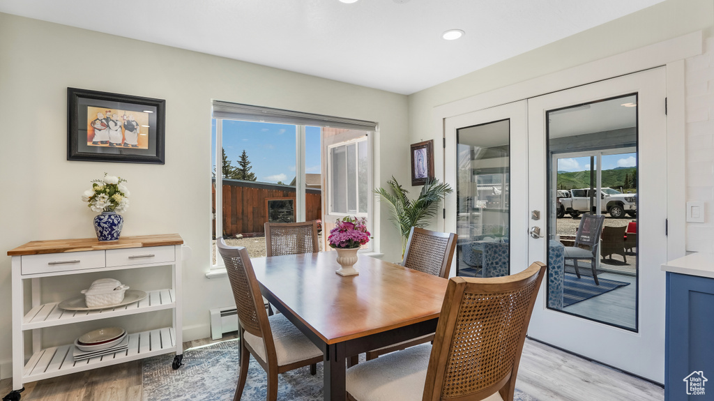Dining space with french doors, light wood-type flooring, a baseboard heating unit, and recessed lighting