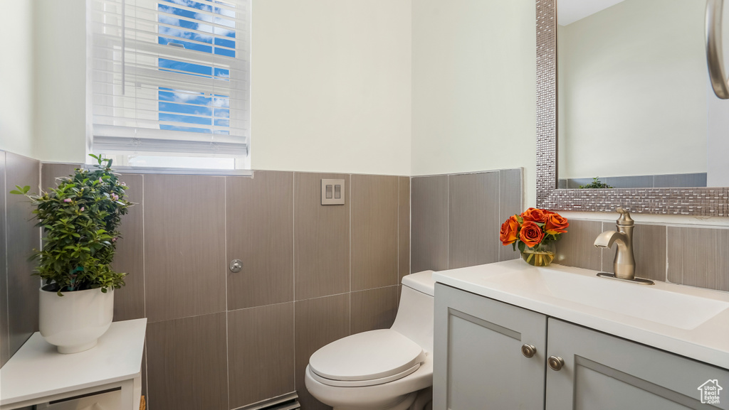 Bathroom with vanity, tile walls, and a wainscoted wall