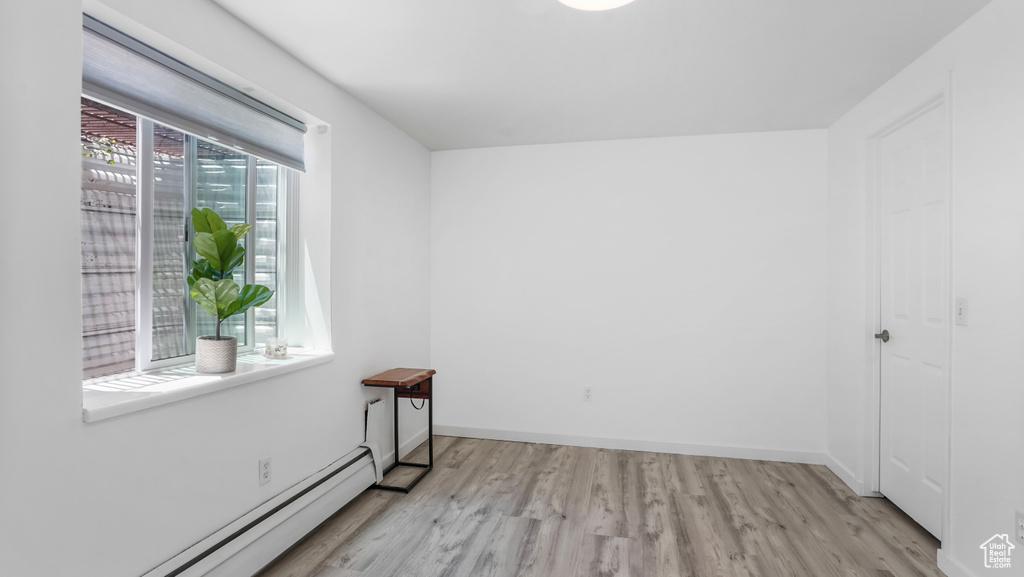Unfurnished room with baseboard heating and light wood-style flooring