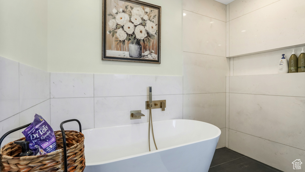 Bathroom featuring tile walls, a freestanding tub, and tile patterned floors