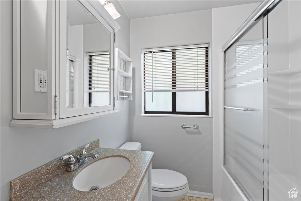 Bathroom with vanity and combined bath / shower with glass door