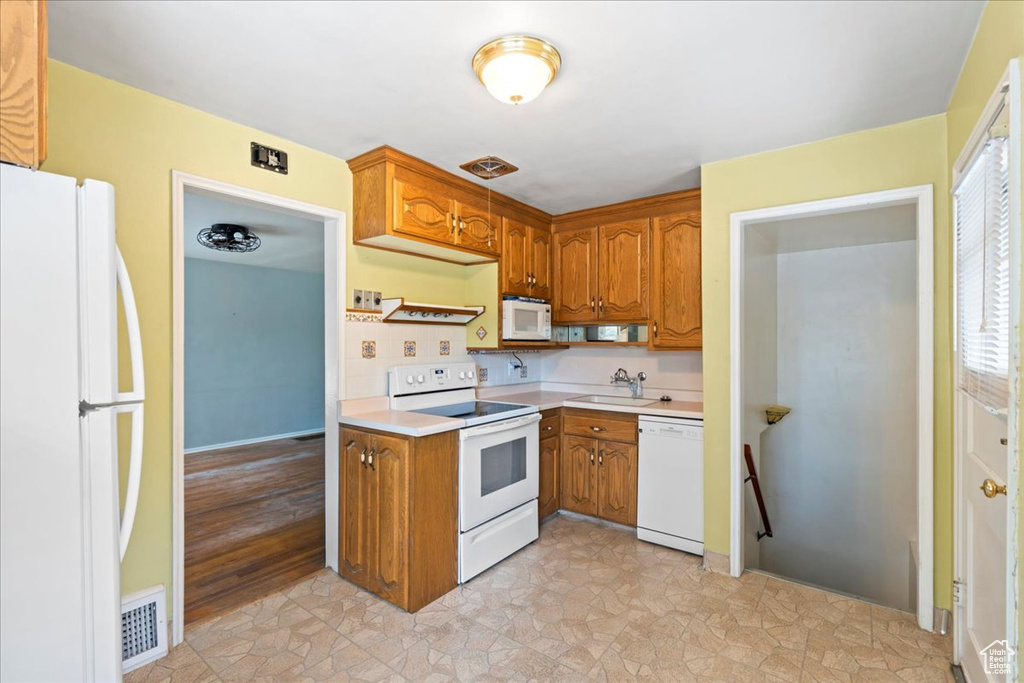 Kitchen featuring white appliances, light countertops, and brown cabinets
