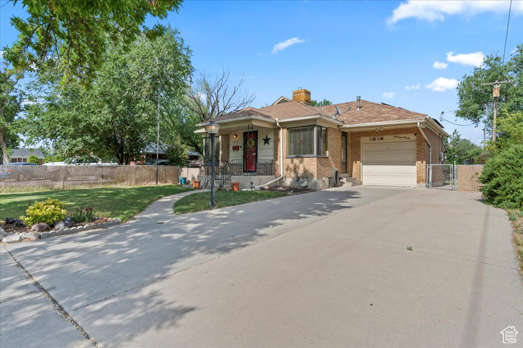 View of front of property featuring a garage, driveway, a gate, brick siding, and a chimney