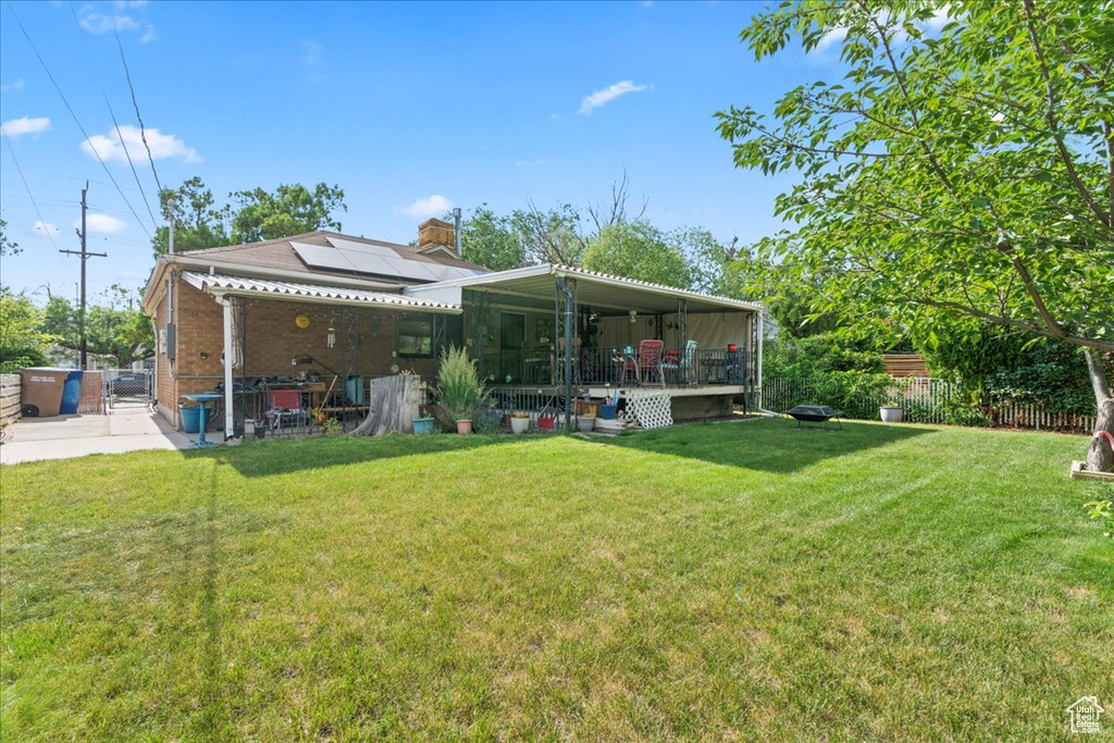 Back of property featuring solar panels, a patio, brick siding, and a chimney