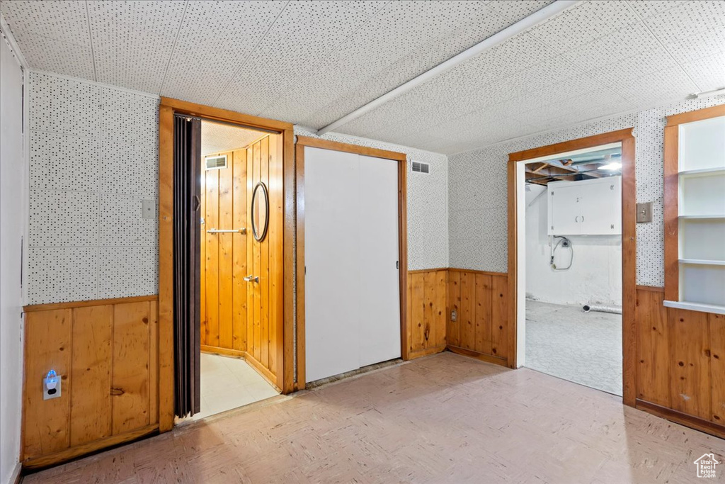 Unfurnished bedroom featuring a wainscoted wall, wood walls, wallpapered walls, and connected bathroom