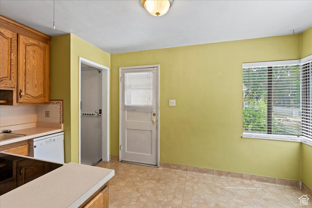 Kitchen with white dishwasher, light countertops, and healthy amount of natural light