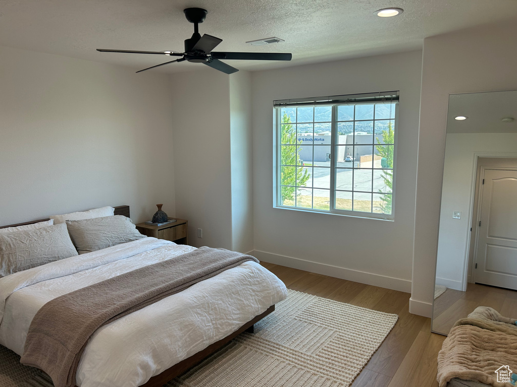 Bedroom featuring light wood-style floors, ceiling fan, recessed lighting, and a textured ceiling