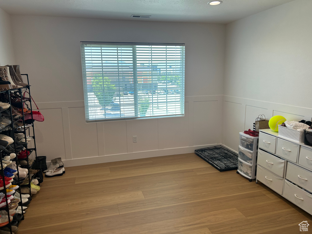 Bedroom with a decorative wall, light wood finished floors, wainscoting, and recessed lighting