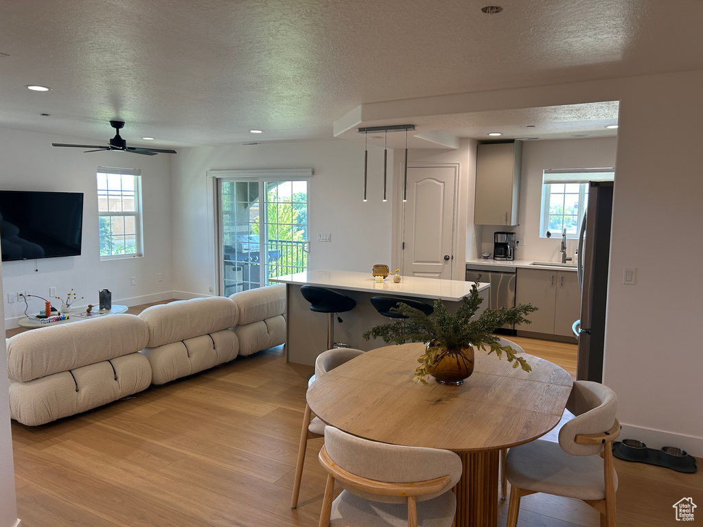 Dining space featuring a textured ceiling, light wood finished floors, ceiling fan, and recessed lighting