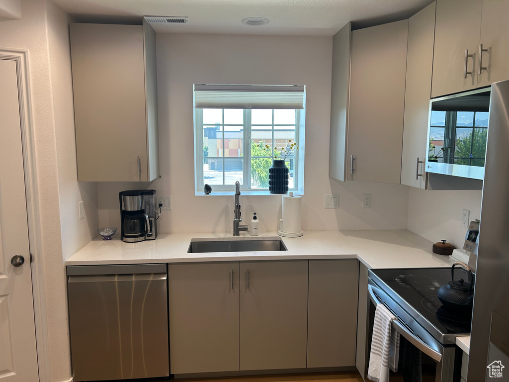 Kitchen featuring stainless steel appliances, gray cabinets, and light countertops
