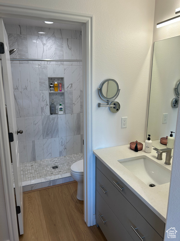 Bathroom with a tile shower, vanity, and wood finished floors