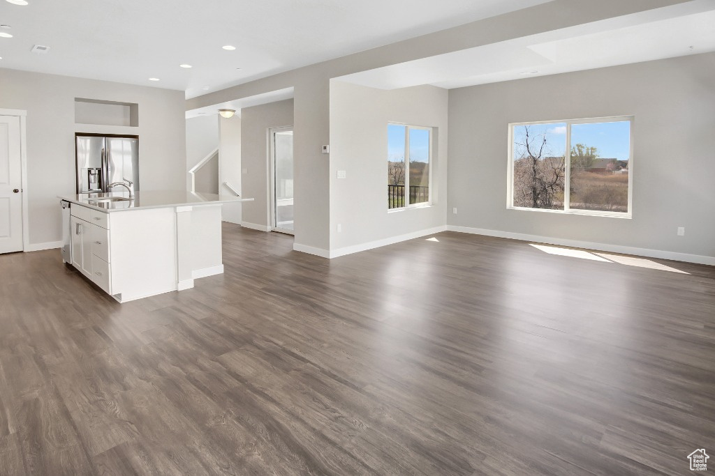 Unfurnished living room featuring recessed lighting and dark wood-style flooring