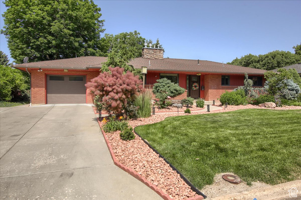 Ranch-style home featuring driveway, brick siding, a garage, and a chimney