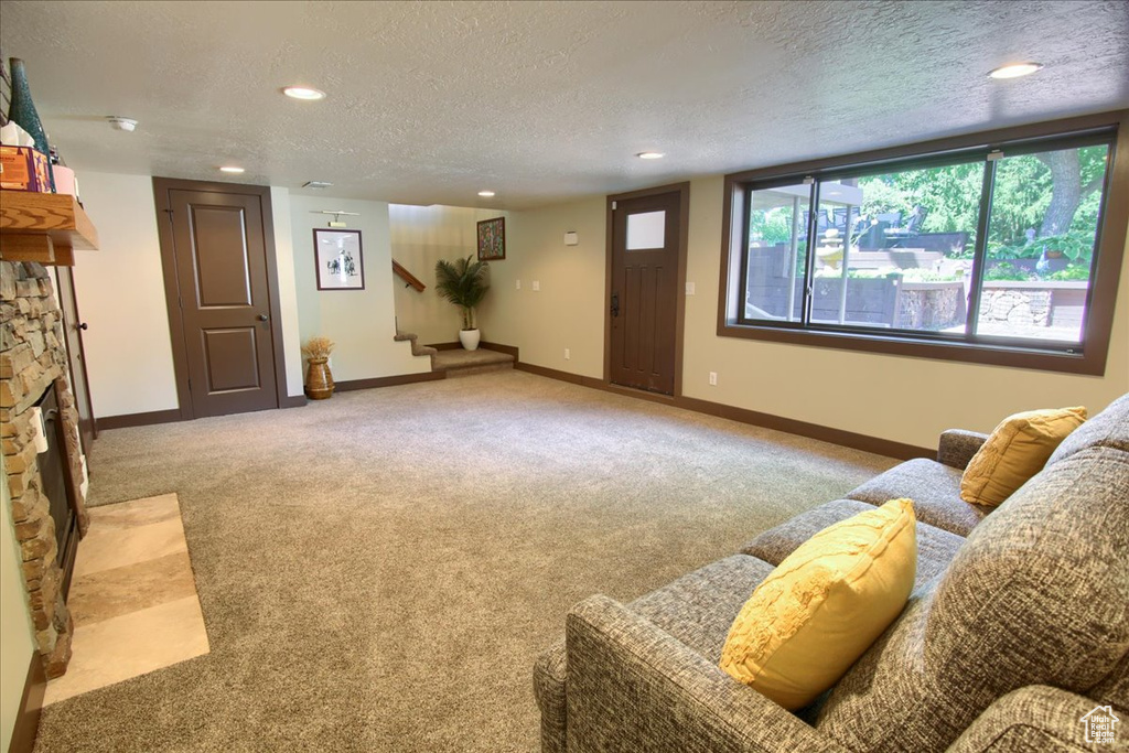 Living room featuring stairway, light carpet, a textured ceiling, a fireplace, and recessed lighting