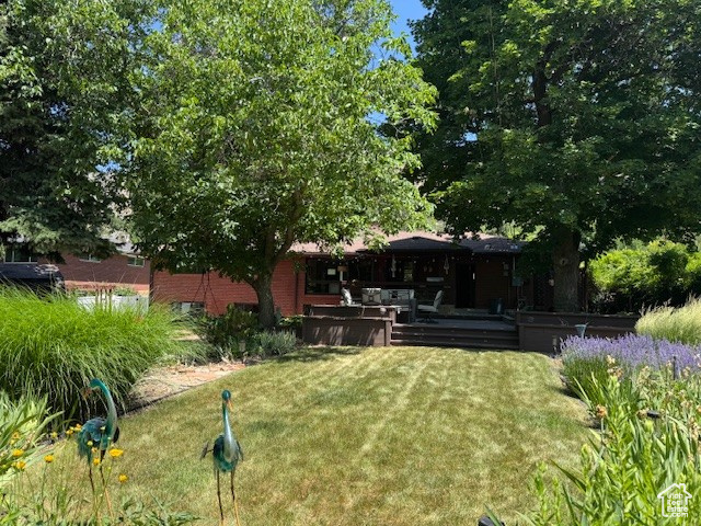 View of grassy yard featuring a wooden deck