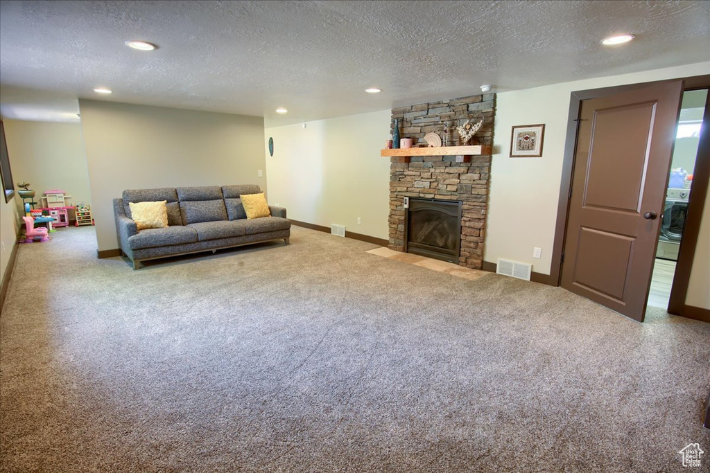 Living room with a textured ceiling, carpet floors, recessed lighting, and a fireplace