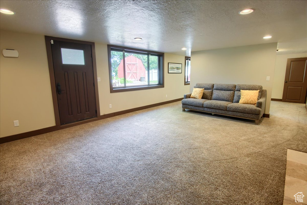 Living area with light carpet, a textured ceiling, and recessed lighting
