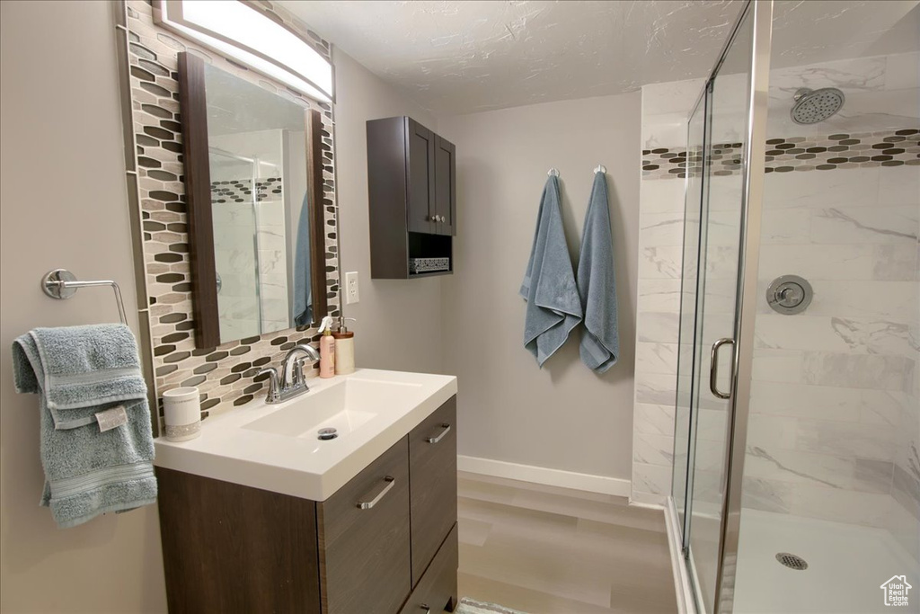 Full bath with vanity, a stall shower, decorative backsplash, and a textured ceiling