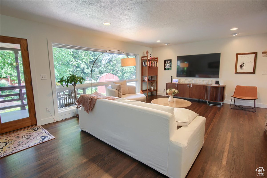 Living room with dark wood-type flooring, recessed lighting, and a textured ceiling