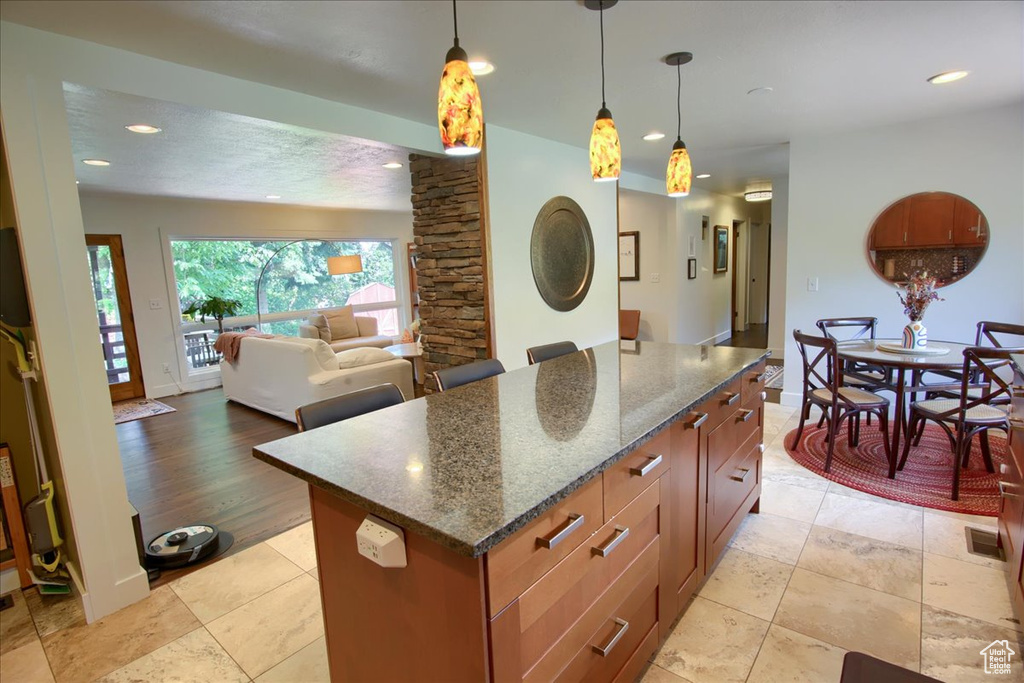 Kitchen with a center island, hanging light fixtures, recessed lighting, dark stone counters, and open floor plan