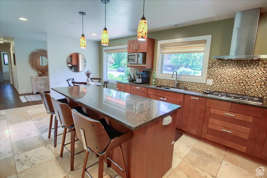 Kitchen with wall chimney range hood, appliances with stainless steel finishes, brown cabinets, decorative backsplash, and recessed lighting