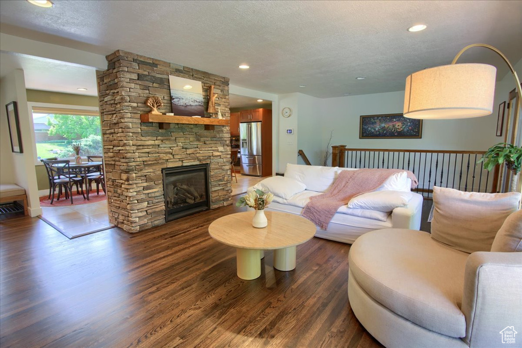 Living area featuring wood finished floors, a textured ceiling, recessed lighting, and a stone fireplace