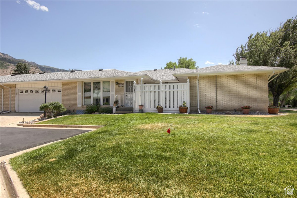 Ranch-style house featuring brick siding, asphalt driveway, a garage, and a front yard