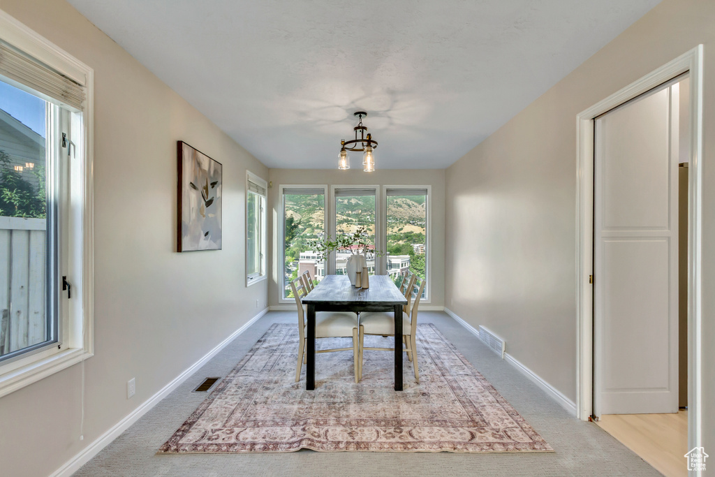 Carpeted dining space with a chandelier and baseboards