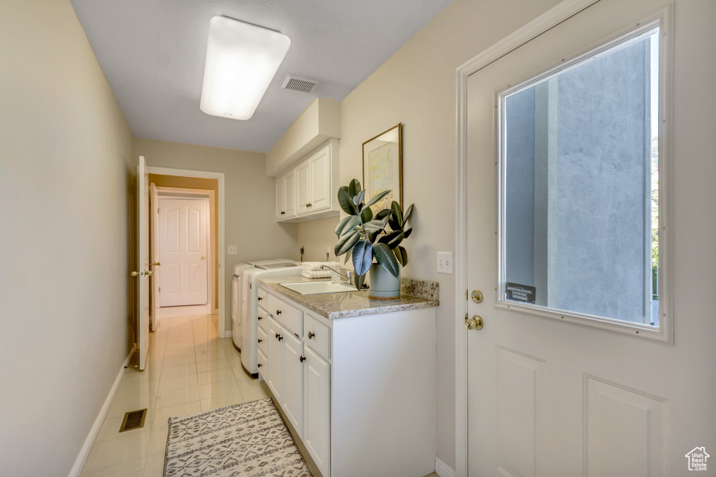 Laundry room with washer and dryer, cabinet space, and light tile patterned flooring