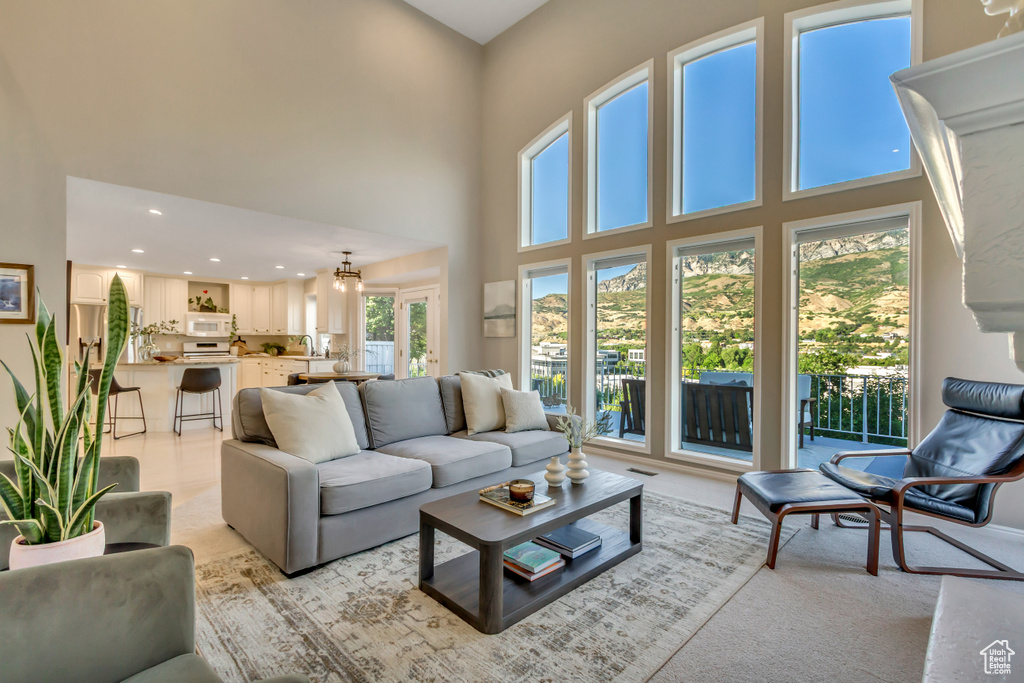 Living area featuring a towering ceiling, recessed lighting, and light colored carpet