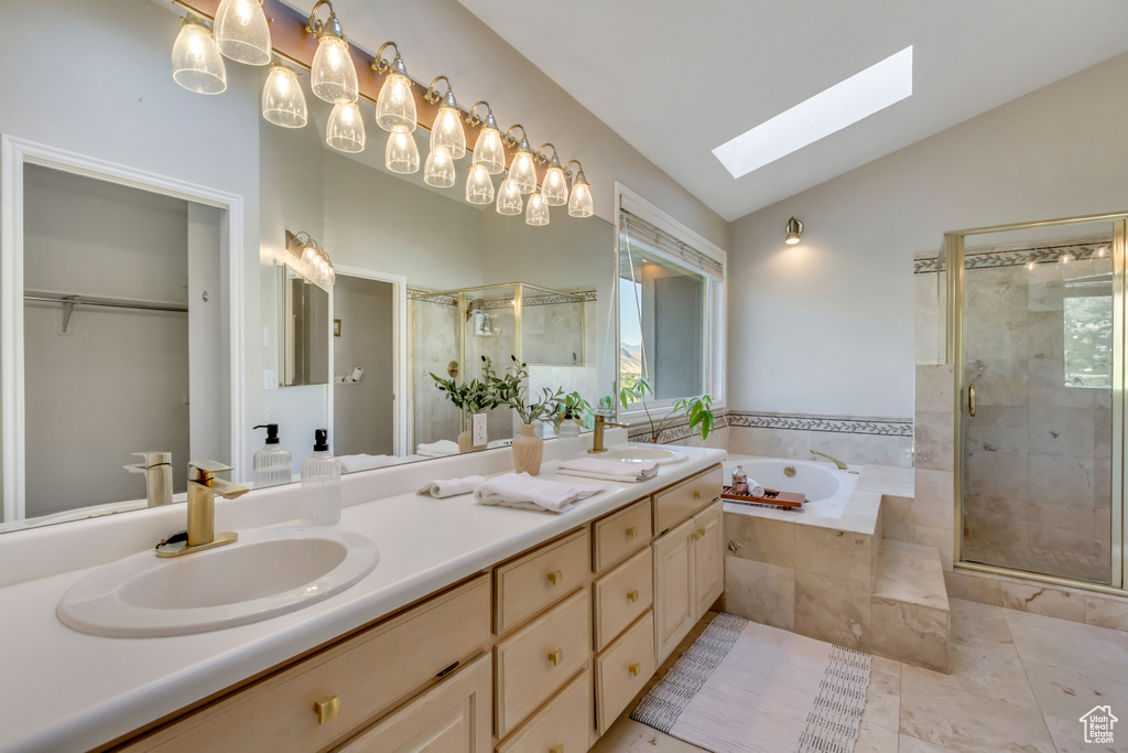 Bathroom with vaulted ceiling, a skylight, a stall shower, a garden tub, and double vanity