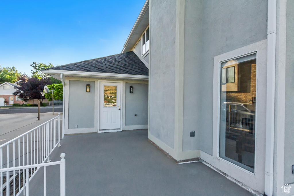 View of exterior entry featuring roof with shingles and stucco siding