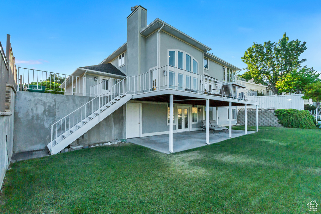 Rear view of property featuring stairway, a chimney, a patio, a deck, and stucco siding