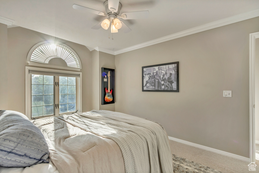 Carpeted bedroom with a ceiling fan and ornamental molding