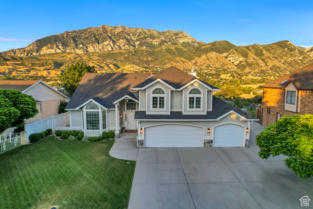 View of front facade featuring a mountain view, driveway, a shingled roof, an attached garage, and stucco siding
