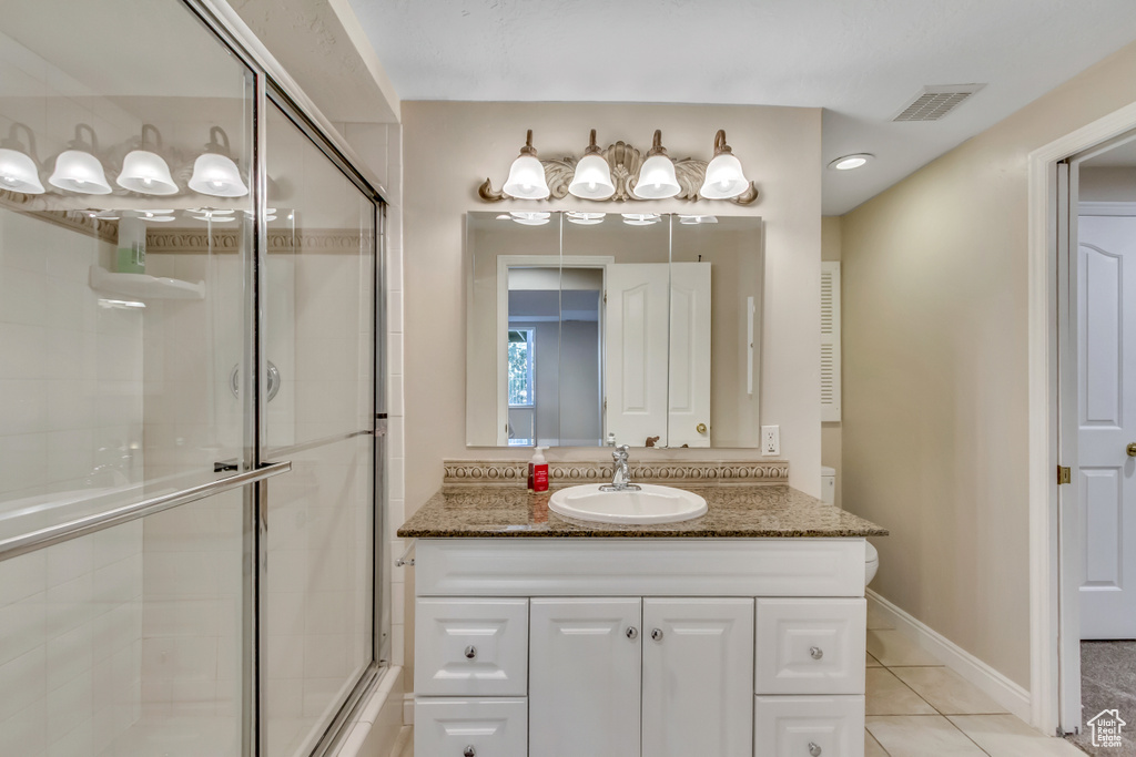 Full bath featuring a tile shower, vanity, and tile patterned floors