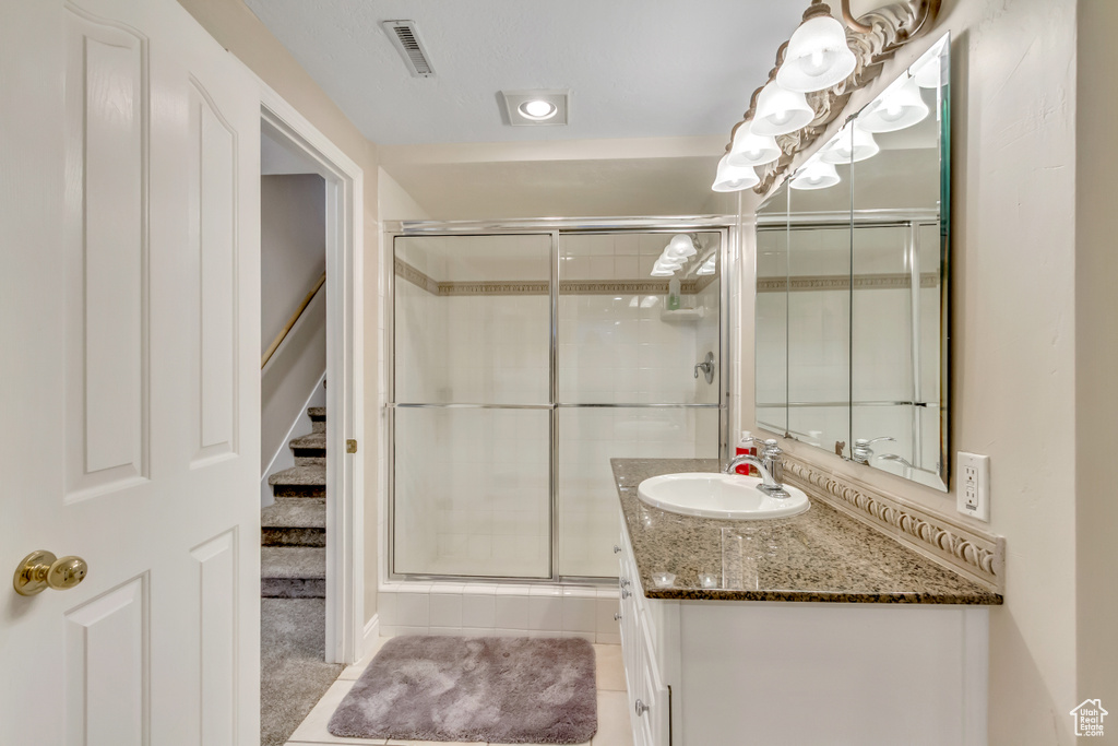 Full bath with vanity, a shower stall, and tile patterned flooring