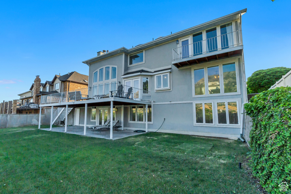 Rear view of property featuring a patio, stucco siding, stairs, and a wooden deck