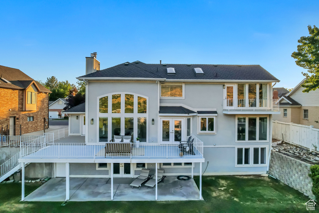 Back of house with french doors, a patio area, stucco siding, a chimney, and a wooden deck